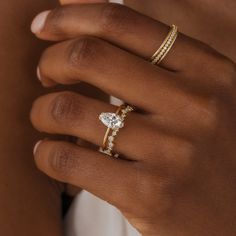 a woman's hand with three different rings on her left and the middle finger