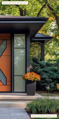 an orange front door with two planters on each side and trees in the background