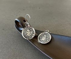 Earrings mayan calendar pendant sterling silver mayan calendar charm earrings for woman silver jewelry gift for her handmade earrings gift These handcrafted Mayan calendar earrings are exquisitely crafted from .925 silver and feature diamond cut accents for a sparkling finish. The small notches around the pendants are polished to a high shine for a beautiful display of light and color. Item Overview *Handmade *Made in Mexico *Ships from CA, USA Item Details *Length: 1.37 in (3.5 cm) *Charm diame Symbolic Drop Earrings Jewelry As Gift, Symbolic Drop Earrings Jewelry Gift, Symbolic Drop Earrings As A Gift, Artisan Dangle Charms Jewelry, Adjustable Silver Medallion Jewelry, Artisan Silver Pendant Earrings, Sterling Silver Dangle Jewelry Stamped 925, Antique Silver Charms Sterling Silver Jewelry, Antique Silver Sterling Silver Charm Jewelry