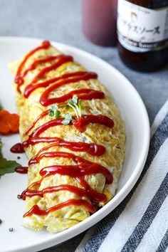 an omelet covered in ketchup sitting on a plate next to vegetables