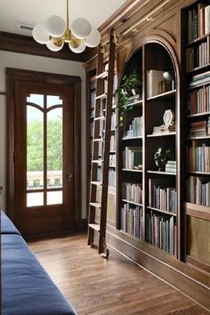 a living room filled with lots of books on top of a hard wood floor next to a window