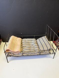 three folded towels are sitting on a metal rack next to a black wall and white table