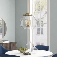 a dining room table with blue chairs and a round glass chandelier hanging from the ceiling