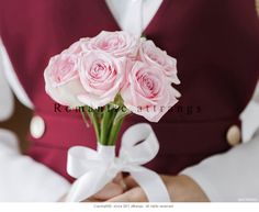 a bouquet of pink roses is held by a woman in a red vest and white shirt