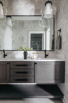 a bathroom with two sinks, mirrors and lights