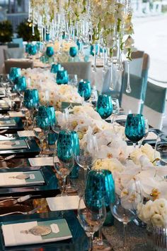 a long table is set with teal and white flowers