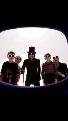 four people wearing sunglasses and hats are standing in front of a mirror with the reflection of them