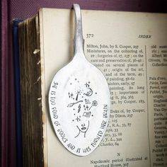 an old book with a spoon on it and a hand - stamped medallion hanging from the side