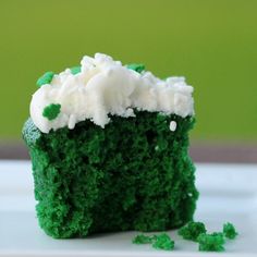 a green cake with white frosting and shamrock sprinkles on the top