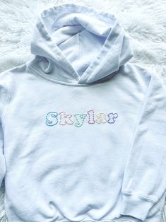 Personalized hand embroidered hooded sweatshirt.  Created on a white hooded sweatshirt with simple stitching in an array of pastels.  A name, location or a simple word all work great for this custom design.  This listing is for one single name or word only.  Please contact me if you're looking to add additional text before ordering.  Each sweatshirt is hand embroidered, made to order and customized to your preferences to create a one-of-a-kind item.  These sweatshirts make for a thoughtful, unique and special gift.  I will be using white unisex  hooded sweatshirts.  Please reference the toddler and youth size charts pictured for measurements.  If you'd like a different sweatshirt color option please send me a message and I will try to accommodate!   In the personalization box please includ Spring Cotton Hoodie With Embroidered Logo, White Cotton Sweatshirt With Custom Embroidery, Spring Hooded Sweatshirt With Embroidered Logo, White Hoodie With Embroidered Graphics For Fall, White Hoodie With Custom Embroidery For Fall, Cotton Hoodie With Embroidered Text And Long Sleeves, Long Sleeve Cotton Hoodie With Embroidered Text, Cotton Long Sleeve Hoodie With Embroidered Text, Casual White Sweatshirt With Machine Embroidery