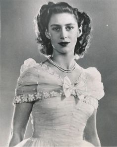 an old black and white photo of a woman in a dress with pearls on it