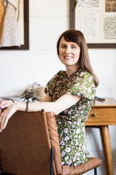 a woman sitting in a chair with her arm on the back of a brown bag