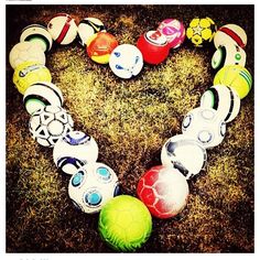 a heart made out of soccer balls on the ground