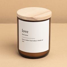 a candle with a wooden lid on top of a brown table next to a wall