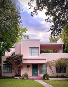 a pink house with trees and bushes around it