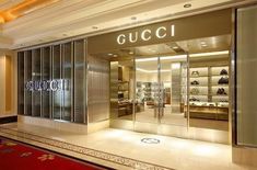 a gucci store in the middle of a mall with its glass doors open and lights on