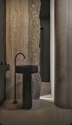 a black sink sitting next to a tall stone wall in a bathroom under a mirror