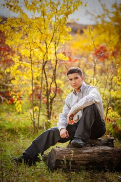 a young man is sitting on a log in the woods