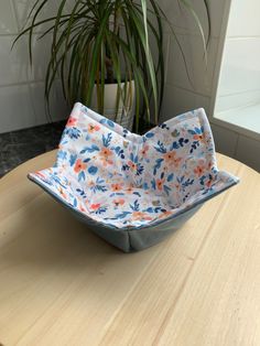 a bowl sitting on top of a wooden table next to a potted plant