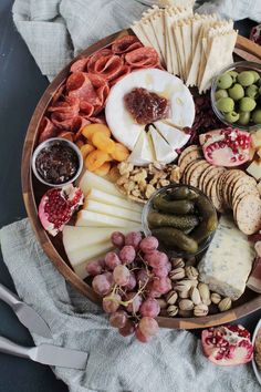 a wooden platter filled with cheese, crackers and other foods on top of a table