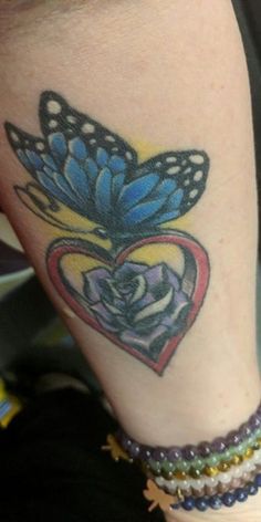 a woman's leg with a butterfly tattoo on it and a rose in the center