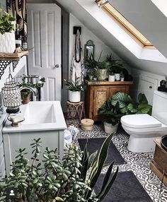 the bathroom is decorated in white and has lots of plants on the floor, along with a toilet