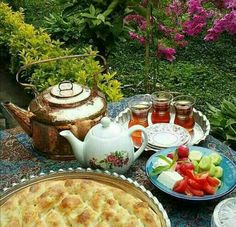 a table topped with pies and fruit next to a tea pot filled with honey