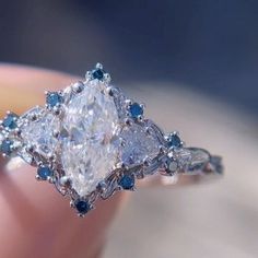 a close up of a person's hand holding a diamond and blue sapphire ring