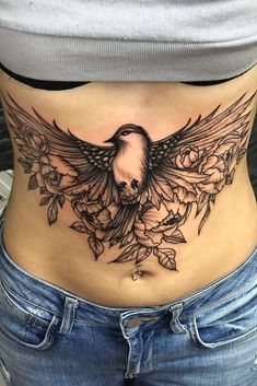 a woman's stomach with a bird tattoo on the side and flowers around it