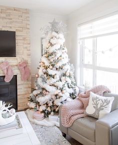 a white christmas tree in a living room with pink and silver ornaments on the branches