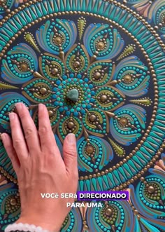 a person's hand touching the center of a blue and green circular artwork piece