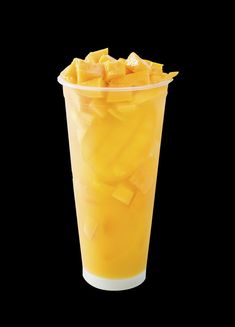 a plastic cup filled with sliced mangoes on top of a black background, in front of a black backdrop