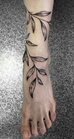 a tattoo on the foot of a woman's foot with leaves growing out of it