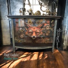 an old dresser with gears painted on the front and sides, sitting in a room next to a window