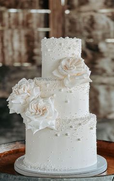 a three tiered white wedding cake with flowers on top