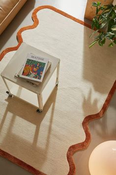 a table with a magazine on it in front of a couch and potted plant