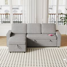 a gray couch sitting on top of a white rug