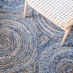 a blue rug with circles on it in front of a chair and side table that has a white wicker chair next to it