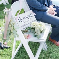 a person sitting in a chair with flowers on the side and a sign that says reserved