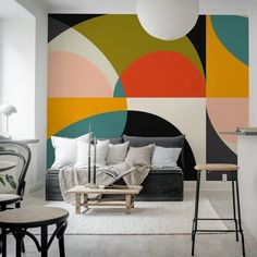 a living room filled with furniture next to a wall painted in different colors and shapes