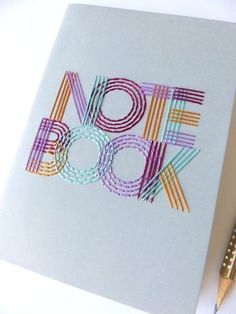 an open notebook with the word book cut out in colorful strips next to a pencil