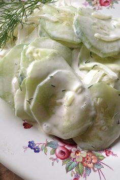 a white plate topped with cucumbers covered in sour cream and dill pickle