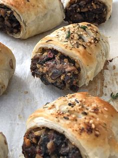 several rolls with meat and vegetables on top of paper