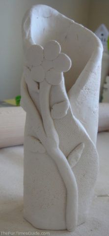 a white vase sitting on top of a table covered in paper mache flowers and leaves