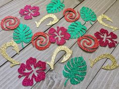 some glittered paper flowers and leaves on a wooden surface