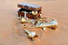 an old fashioned pirate chest and brass bells on the sand in the desert with a rope