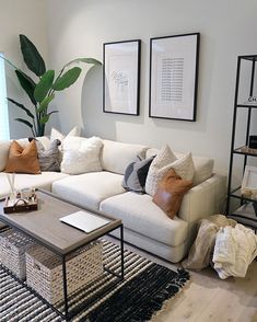 a living room with white couches and pillows on top of the couch, next to a coffee table