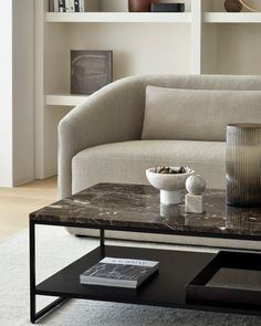 a living room with a couch, coffee table and bookshelf in the background