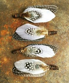 three white feathers with black spots on them sitting on a rusty surface next to each other