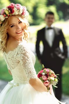 a woman in a white wedding dress and a man in a tuxedo standing behind her